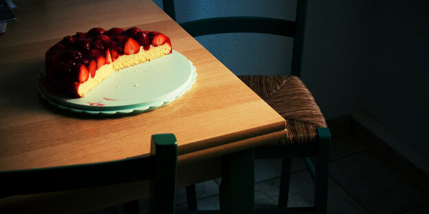 Eine angeschnittene Erdbeertorte steht auf einem Küchentisch Eine angeschnittene Erdbeertorte steht auf einem Küchentisch