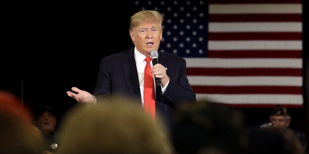 Donald Trump steht auf der Bühne und hält ein Mikrofon in der Hand Donald Trump steht auf der Bühne und hält ein Mikrofon in der Hand