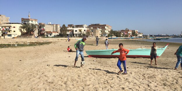 Kinder spielen am Strand des Dorfes.