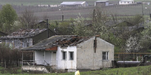Ein Haus mit einem Dachschaden steht auf einer grünen Wiese Ein Haus mit einem Dachschaden steht auf einer grünen Wiese