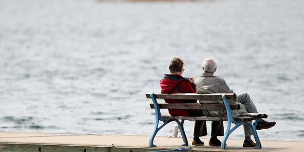 Zwei ältere Menschen sitzen auf einer Bank am See Zwei ältere Menschen sitzen auf einer Bank am See
