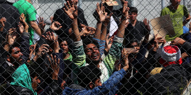 Menschen protestieren hinter einem Zaun Menschen protestieren hinter einem Zaun