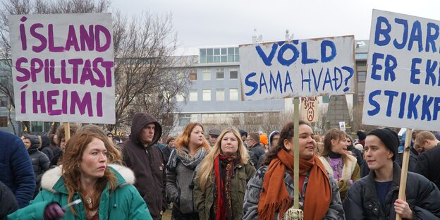 Menschen protestieren mit farbig beschrifteten Schildern