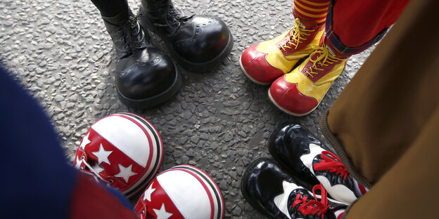 Vier Paar Füße mit Clownsschuhen Vier Paar Füße mit Clownsschuhen