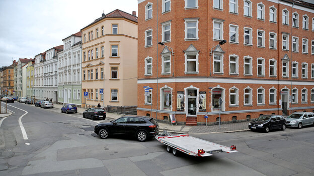 Eine Straßenkreuzung mit Altbauten und Autos vor den Häusern Eine Straßenkreuzung mit Altbauten und Autos vor den Häusern