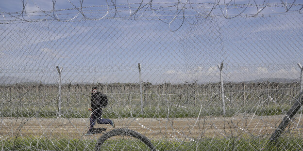 Ein junger Flüchtling rennt am Zaun an der mazedonisch-griechischen Grenze entlang Ein junger Flüchtling rennt am Zaun an der mazedonisch-griechischen Grenze entlang