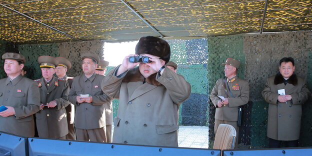 Nordkoreas Machthaber Kim Jong Un guckt in ein Fernglas Nordkoreas Machthaber Kim Jong Un guckt in ein Fernglas