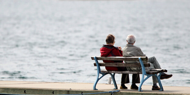 Zwei Rentner_innen sitzen auf einer Bank vor einem See Zwei Rentner_innen sitzen auf einer Bank vor einem See