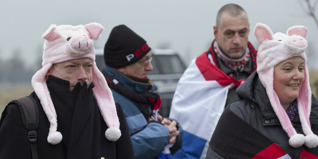 Pegida-Anhänger_innen tragen Schweinchen-Mützen auf dem Kopf Pegida-Anhänger_innen tragen Schweinchen-Mützen auf dem Kopf