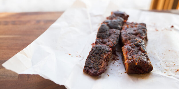 Auf einem Stück Papier liegen zwei Stücke von veganem Grillfleisch Auf einem Stück Papier liegen zwei Stücke von veganem Grillfleisch