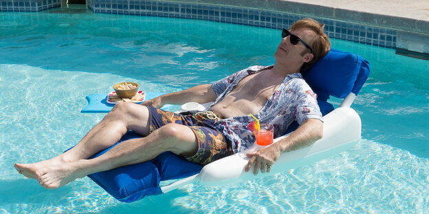 Ein Mann mit Sonnenbrille liegt auf einer Luftmatratze in einem Pool. Es ist Bob Odenkirk Ein Mann mit Sonnenbrille liegt auf einer Luftmatratze in einem Pool. Es ist Bob Odenkirk