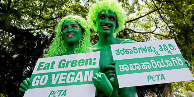 Peta-Aktivisten halten Pro-Vegan-Plakate in die Kamera Peta-Aktivisten halten Pro-Vegan-Plakate in die Kamera