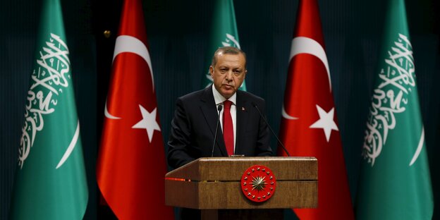 Erdoğan steht am Rednerpult vor türkischen und saudi-arabischen Flaggen Erdoğan steht am Rednerpult vor türkischen und saudi-arabischen Flaggen