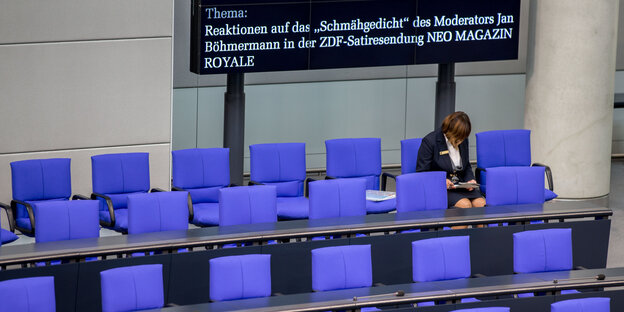 Eine Saalhelferin sitzt im Bundestag, im Hintergrund ein Schild mit der Themenankündigung Eine Saalhelferin sitzt im Bundestag, im Hintergrund ein Schild mit der Themenankündigung