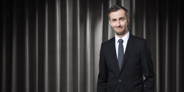 Moderator Jan Böhmermann im Anzug vor einem Vorhang Moderator Jan Böhmermann im Anzug vor einem Vorhang