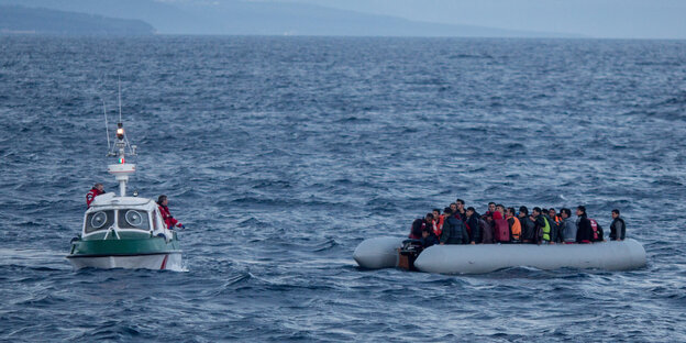 Ein Schlauchboot mit vielen Menschen, daneben ein größeres Boot Ein Schlauchboot mit vielen Menschen, daneben ein größeres Boot