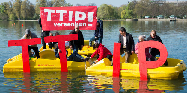 In zwei gelben Schlauchbooten sitzen mehrere Aktivisten, die rote Buchstaben in der Hand haben. Sie ergeben das Wort TTIP In zwei gelben Schlauchbooten sitzen mehrere Aktivisten, die rote Buchstaben in der Hand haben. Sie ergeben das Wort TTIP