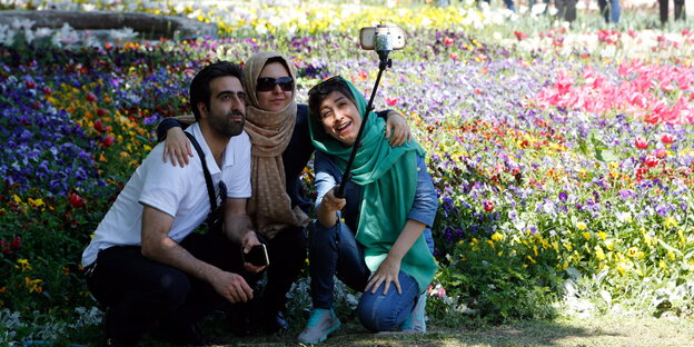 Mann im T-Shirt und zwei Frauen mit Kopftuch machen ein Selfie bei der Blumenausstellung in Karaj, Iran, April 2016 Mann im T-Shirt und zwei Frauen mit Kopftuch machen ein Selfie bei der Blumenausstellung in Karaj, Iran, April 2016