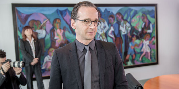 Heiko Maas vor einem bunten Bild, schräg hinter ihm ein Fotograf Heiko Maas vor einem bunten Bild, schräg hinter ihm ein Fotograf