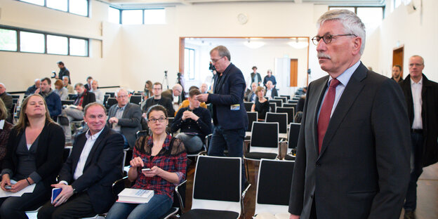 Thilo Sarrazin steht im Anzug vor halb besetzten Stuhlreihen Thilo Sarrazin steht im Anzug vor halb besetzten Stuhlreihen