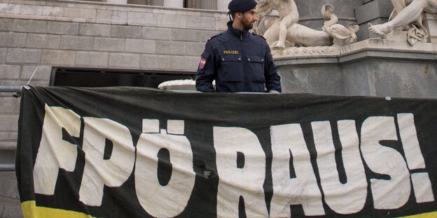 Ein Polizist steht hinter einem Banner mit der Aufschrift "FPÖ RAUS!" Ein Polizist steht hinter einem Banner mit der Aufschrift "FPÖ RAUS!"