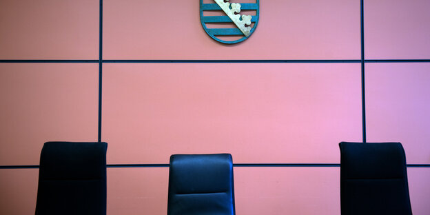 Drei Stühle vor einer Wand, an ihr hängt ein Wappen Drei Stühle vor einer Wand, an ihr hängt ein Wappen