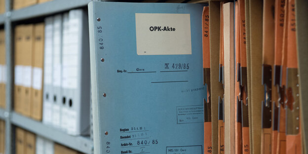 Eine hellblaue Stasi-Akte mit der Aufschrift "OPK" steckt in einem Regal Eine hellblaue Stasi-Akte mit der Aufschrift "OPK" steckt in einem Regal