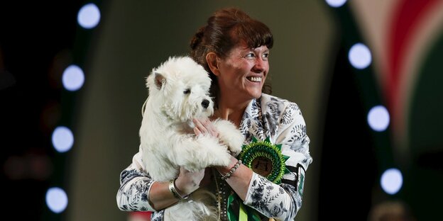 Ein Hund auf dem Arm einer Frau Ein Hund auf dem Arm einer Frau