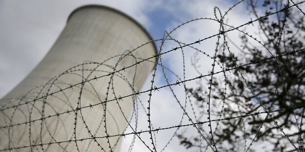 Ein Atommeiler aus der Froschperspektive, im Vordergrund Stacheldraht. Ein Atommeiler aus der Froschperspektive, im Vordergrund Stacheldraht.