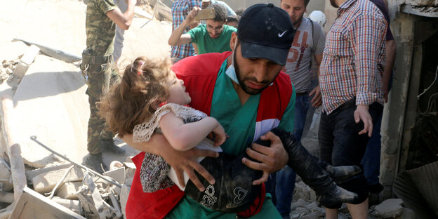Helfer und Kind zwischen Trümmern in Aleppo Helfer und Kind zwischen Trümmern in Aleppo