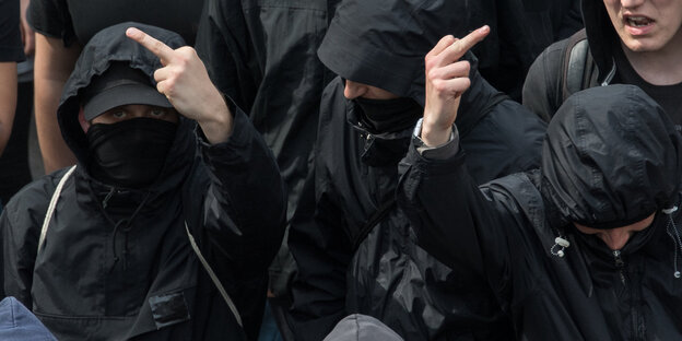 Zwei vermummte Teilnehmer einer Demo zeigen den Stinkefinger Zwei vermummte Teilnehmer einer Demo zeigen den Stinkefinger