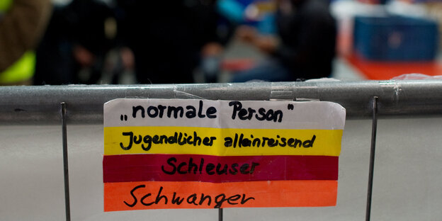 An einem Geländer hängen verschiedenfarbige Armbänder mit den Aufschriften „normale Person“, „Jugendlicher alleinreisend“, Schleuser“, „Schwanger“ An einem Geländer hängen verschiedenfarbige Armbänder mit den Aufschriften „normale Person“, „Jugendlicher alleinreisend“, Schleuser“, „Schwanger“