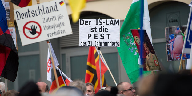Pegida-Teilnehmer_innen halten Schilder und Fahnen hoch Pegida-Teilnehmer_innen halten Schilder und Fahnen hoch