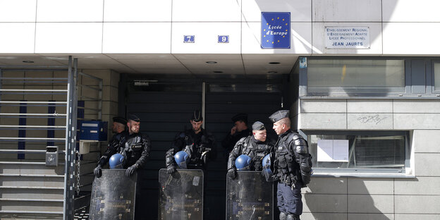 Polizisten bewachen den EIngang des Jean-Jaurès-Gymnasiums, nachdem sie die dort lebenden Flüchtlinge evakuiert haben Polizisten bewachen den EIngang des Jean-Jaurès-Gymnasiums, nachdem sie die dort lebenden Flüchtlinge evakuiert haben