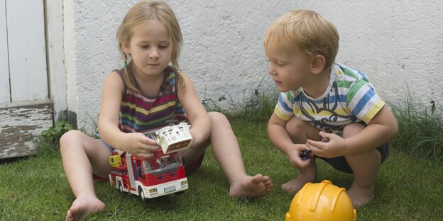 Ein Junge und ein Mädchen spielen mit einem Feuerwehrauto. Ein Junge und ein Mädchen spielen mit einem Feuerwehrauto.