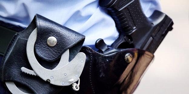 Ein Polizist trägt Handschellen und eine Pistole am Gürtel Ein Polizist trägt Handschellen und eine Pistole am Gürtel