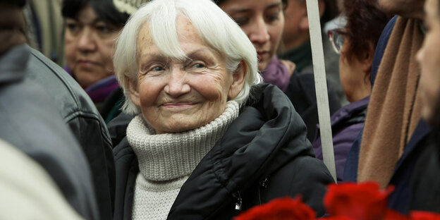 Margot Honecker steht in einer Menschenmenge, vor ihr hält jemand Nelken Margot Honecker steht in einer Menschenmenge, vor ihr hält jemand Nelken