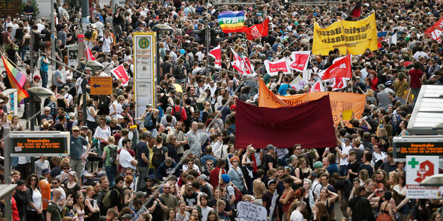 Zahlreiche Menschen stehen mit Bannern an einer Haltestelle vorbei Zahlreiche Menschen stehen mit Bannern an einer Haltestelle vorbei