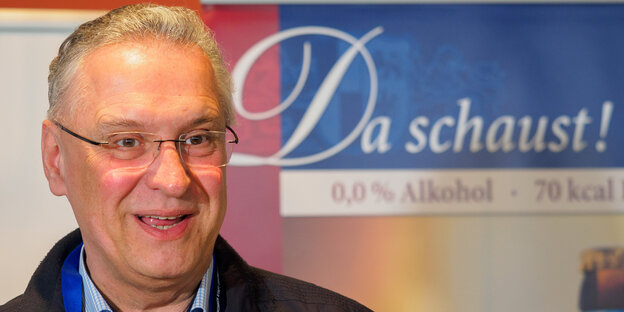 Joachim Herrmann lächelt vor einem Plakat mit der Aufschrift „Da schaust!“ Joachim Herrmann lächelt vor einem Plakat mit der Aufschrift „Da schaust!“