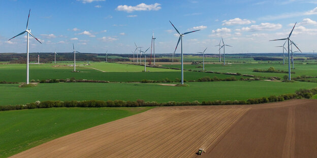 Windräder stehen zwischen Feldern