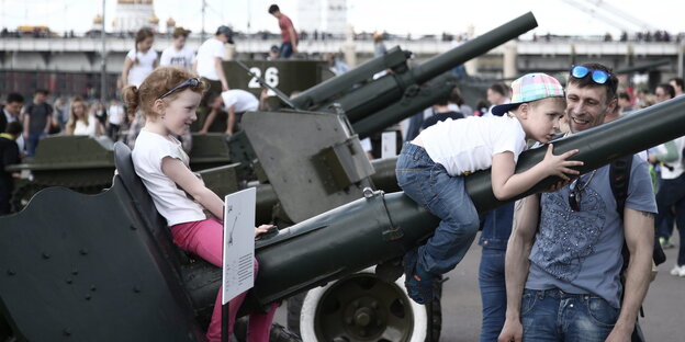Zwei Kinder sitzen auf dem Zielroher eines Panzers Zwei Kinder sitzen auf dem Zielroher eines Panzers