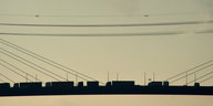LKWs fahren im Sonnenuntergang auf der Köhlbrandbrücke in Hamburg