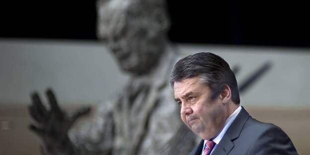 Im Vordergrund Sigmar Gabriel, verschwommen im Hintergrund eine Statue von Willy Brandt Im Vordergrund Sigmar Gabriel, verschwommen im Hintergrund eine Statue von Willy Brandt
