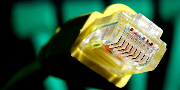 Der Stecker eines Netzwerkkabels vor grün-schwarzem Hintergrund Der Stecker eines Netzwerkkabels vor grün-schwarzem Hintergrund