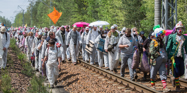 Menschen in weißen Schutzanzügen laufen auf Bahnschienen Menschen in weißen Schutzanzügen laufen auf Bahnschienen
