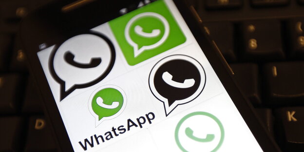 Auf einem weißen Handy-Display ist ein grüner Kreis mit einem weißen Telefonhörer, darunter der Schriftzug Whatsapp
