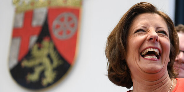 Malu Dreyer lacht neben einem Wappen von Rheinland-Pfalz Malu Dreyer lacht neben einem Wappen von Rheinland-Pfalz