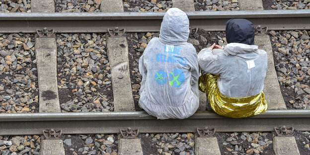Zwei Kohleaktivist*Innen sitzen auf Schienen während der Ende-Gelände-Proteste Zwei Kohleaktivist*Innen sitzen auf Schienen während der Ende-Gelände-Proteste