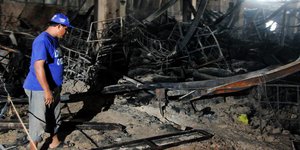 Ein Mann steht in einer ausgebrannten Fabrikhalle