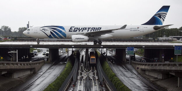 Ein Flugzeug auf einem Rollfeld, dass auf einer Brücke über Schienen und Straßen verläuft Ein Flugzeug auf einem Rollfeld, dass auf einer Brücke über Schienen und Straßen verläuft